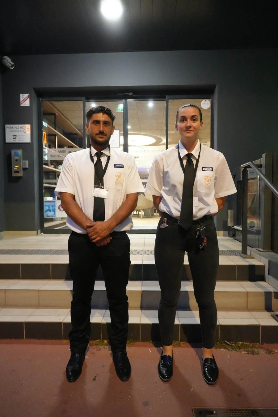 Deux agents de sécurité en poste de nuit devant un hôtel